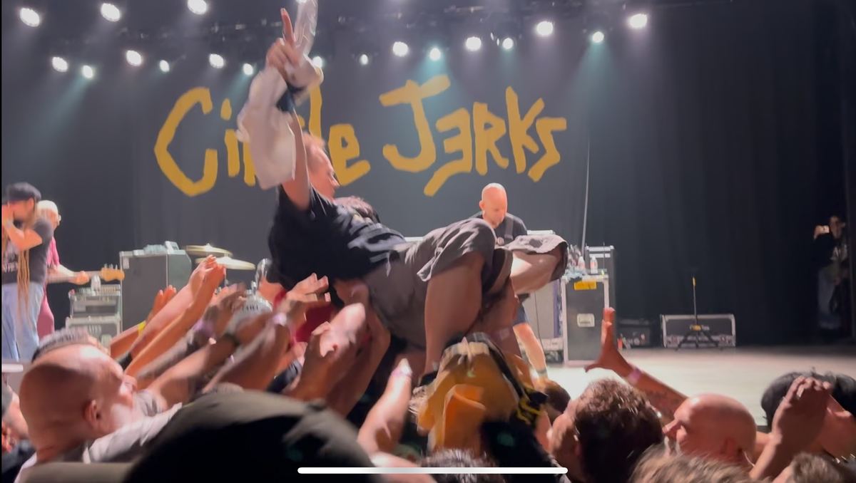 Ryan crowd surfing at a Circle Jerks show, carried on raised hands in front of the stage